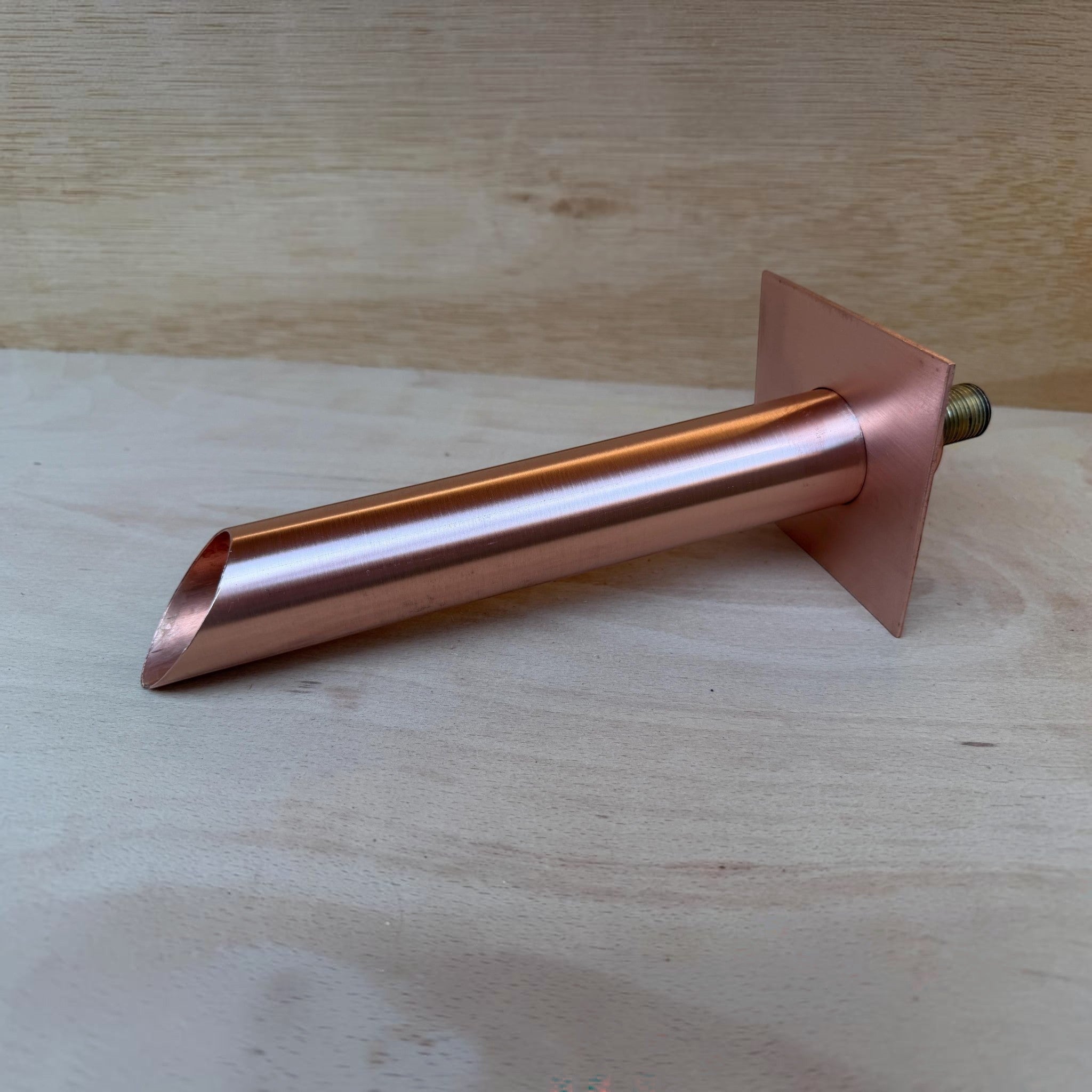 Copper wall spout in a garden water feature